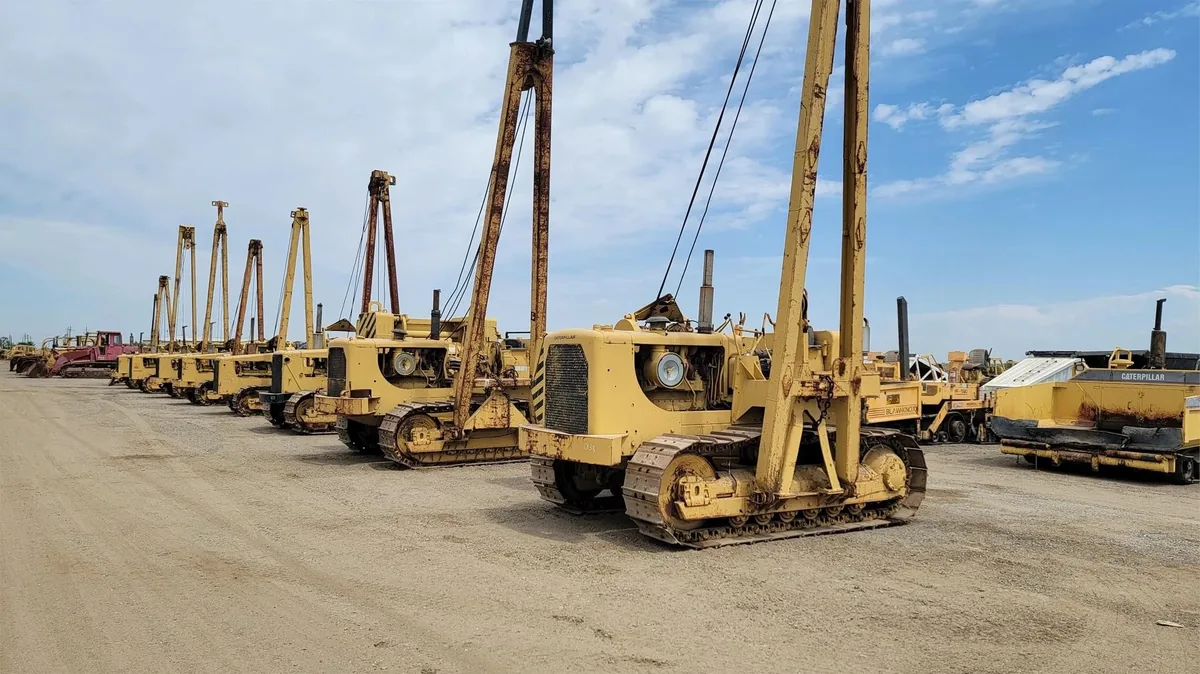 Fleet of 1980s Caterpillar crawler cranes — heavy equipment industry consolidation era