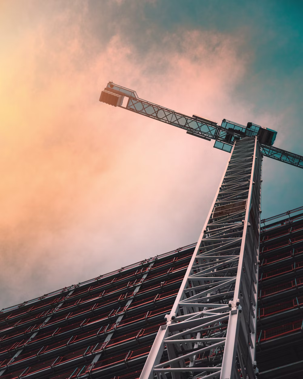 Low angle view of a gray tower crane at golden hour