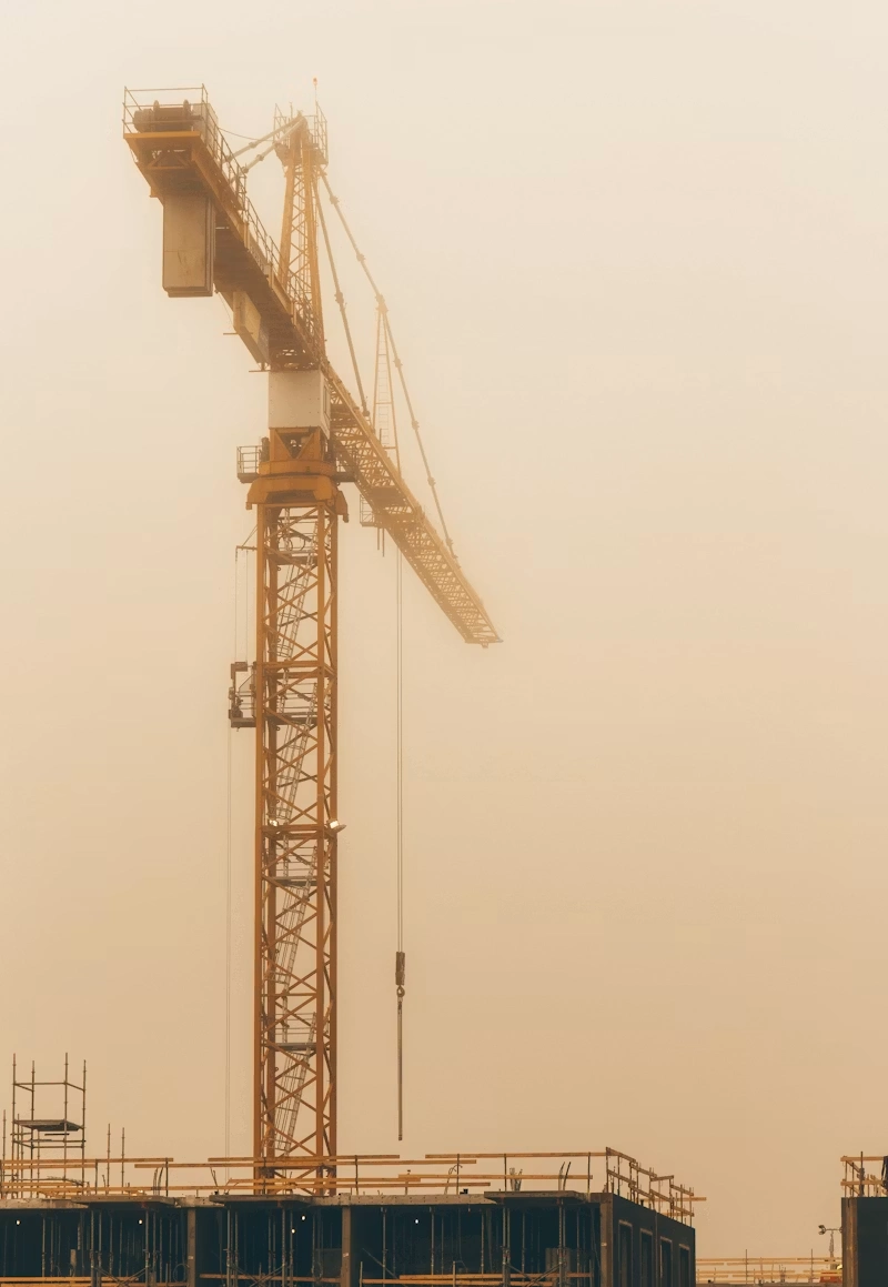 Yellow mobile crane seen from a distance under a gray sky